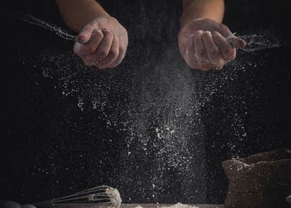 Flour being dusted across the bench