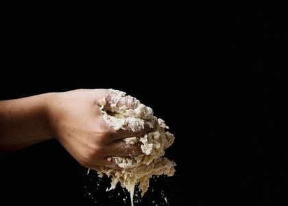A hand working through wet dough