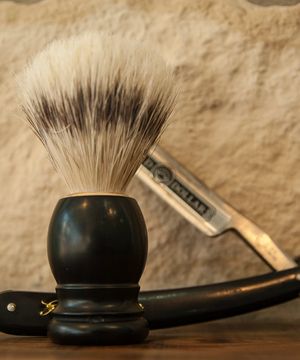 A shaving brush beside a straight razor