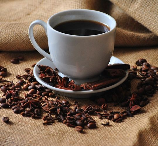 A cup of coffee beside roasted beans